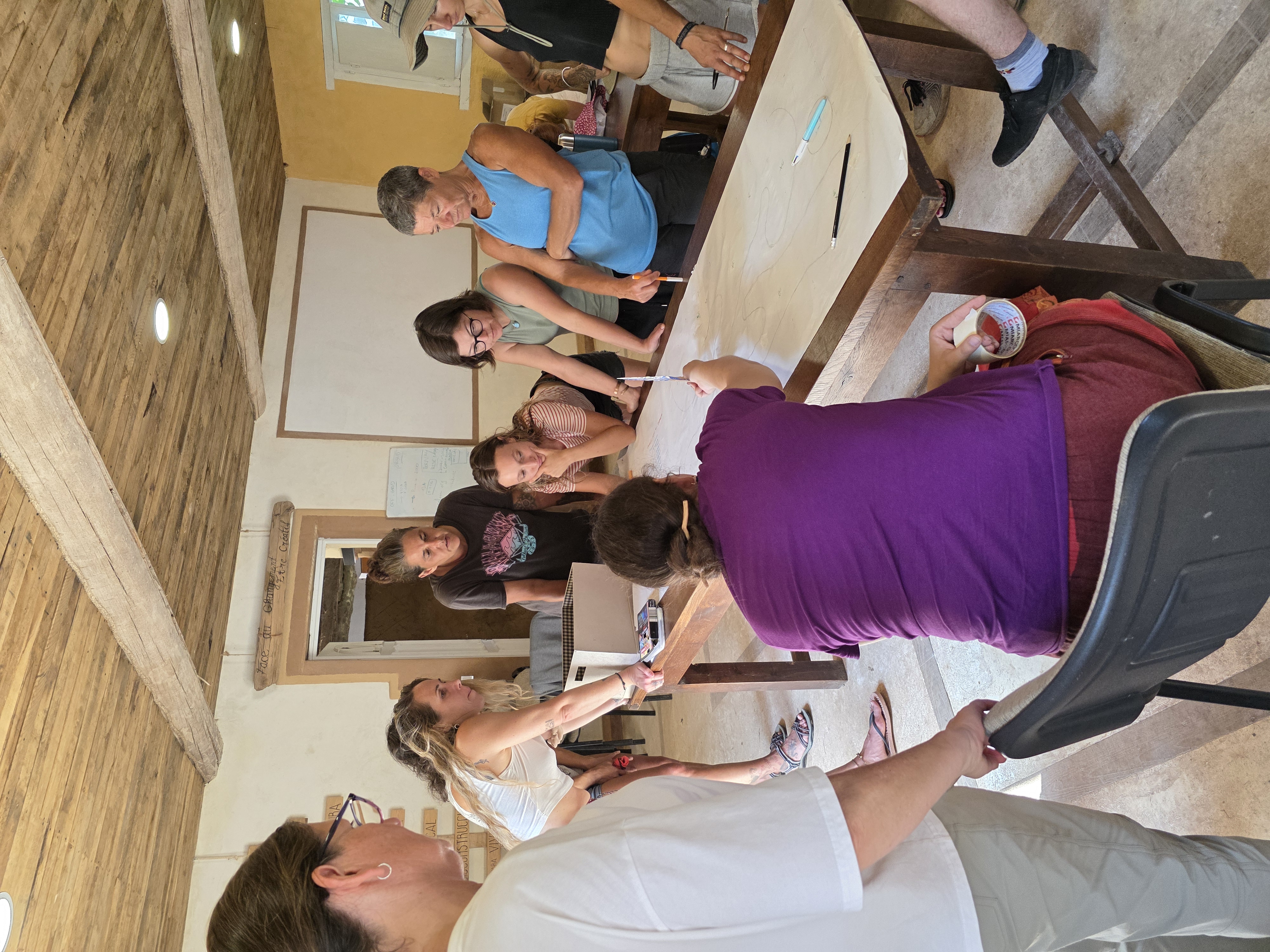 Grupo dibujando juntos el diseño de un bosque de alimentos sobre una mesa larga durante el curso en El Mandala.