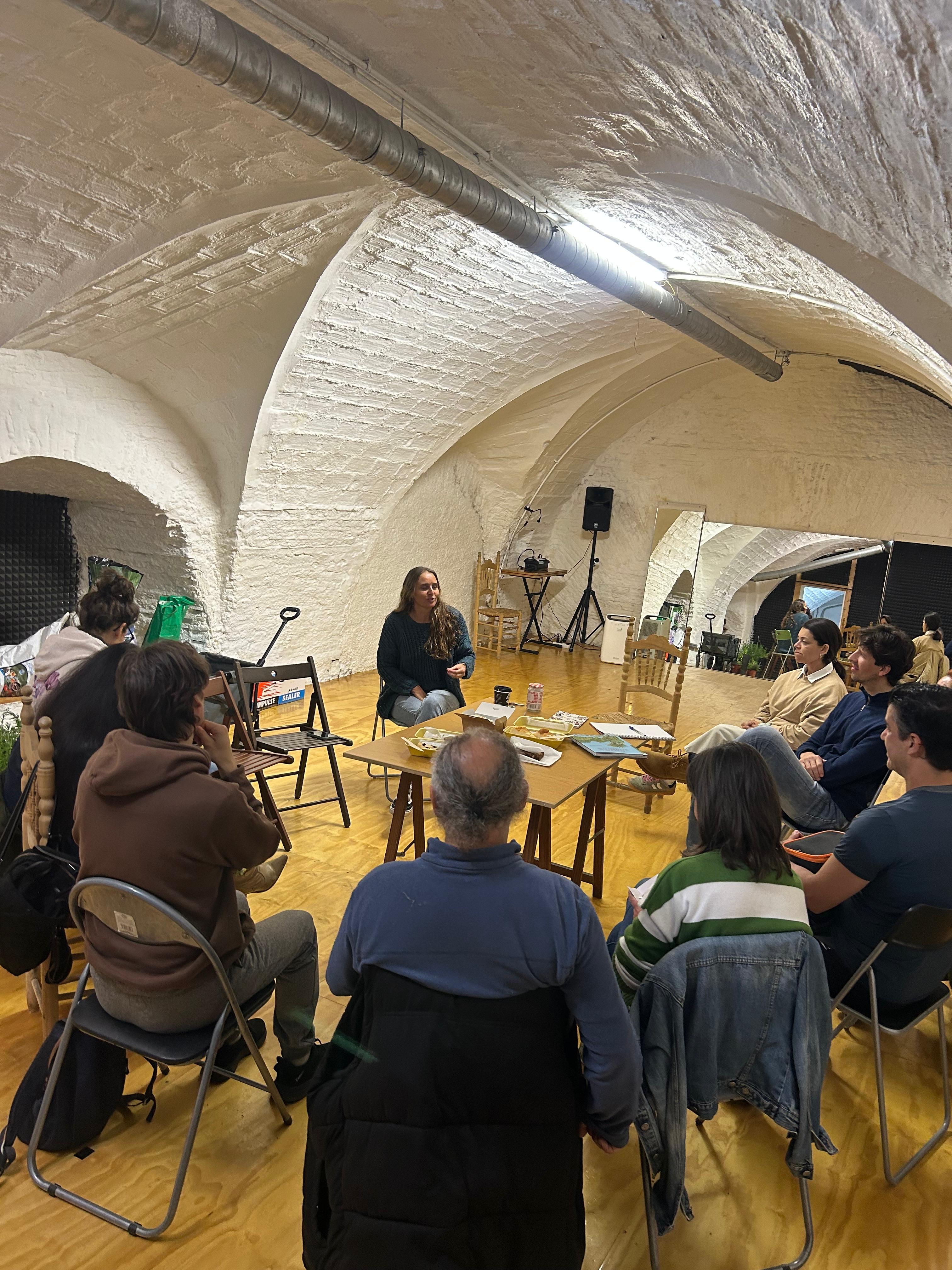 Grupo sentado en círculo bajo una bóveda de piedra encalada durante el taller de hierbas medicinales en Granada.
