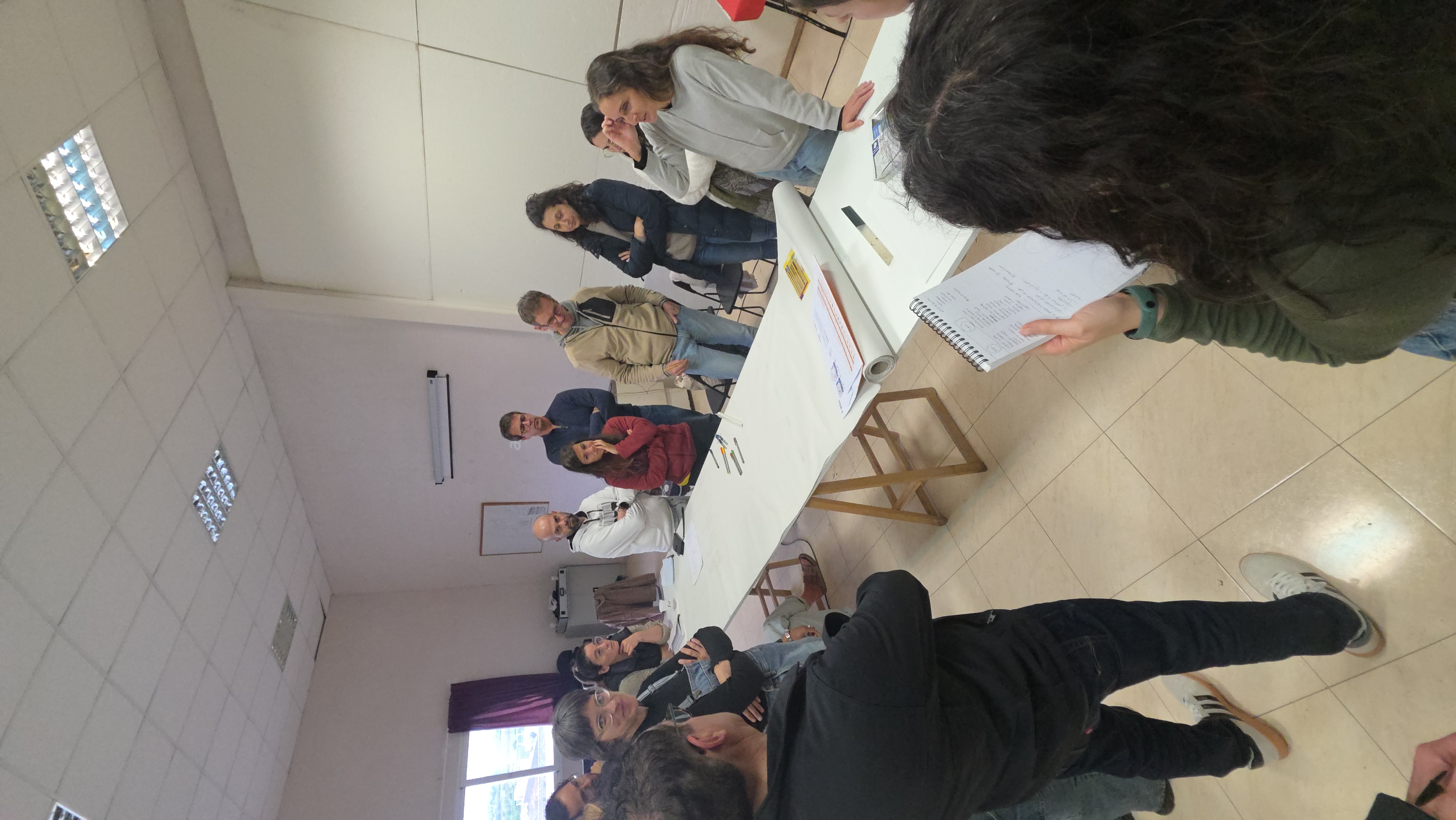 Sesión de diseño en torno a un gran plano de papel en el aula del curso de Valencia.